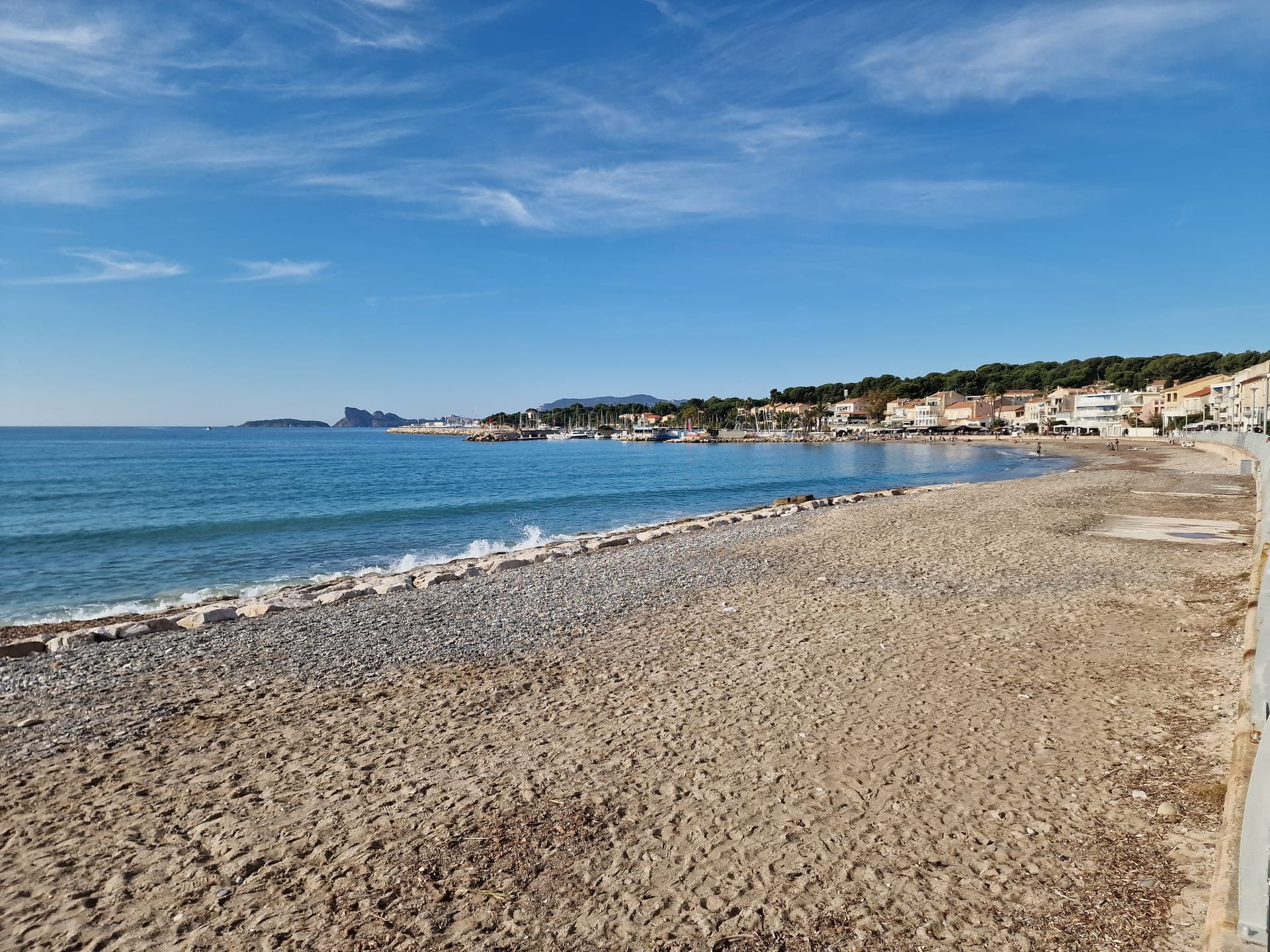 La plage, le port et les façades du littoral de Saint-Cyr-sur-Mer sous un ciel bleu.